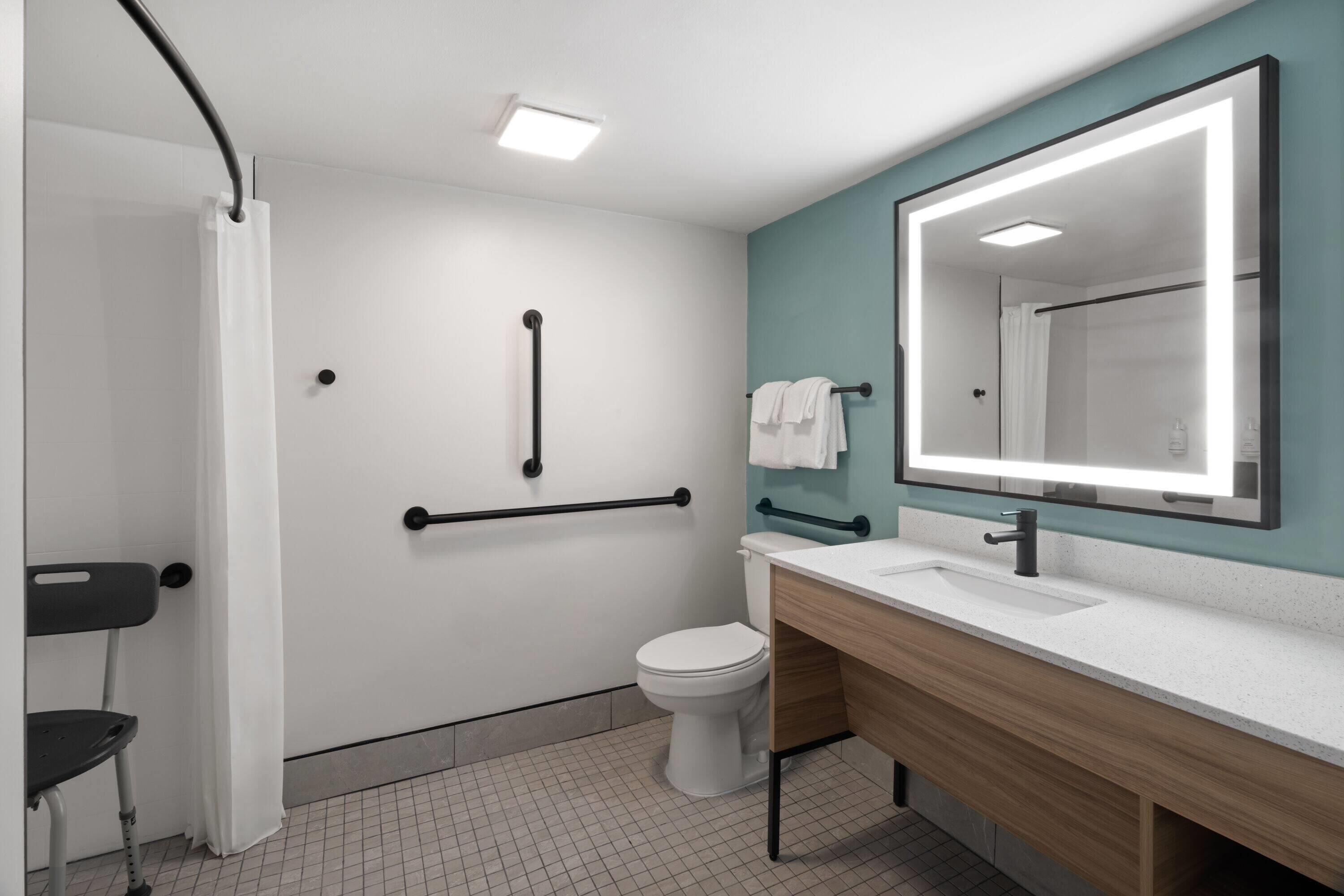 A modern bathroom with a white toilet, a sink with a mirror, and a shower area.