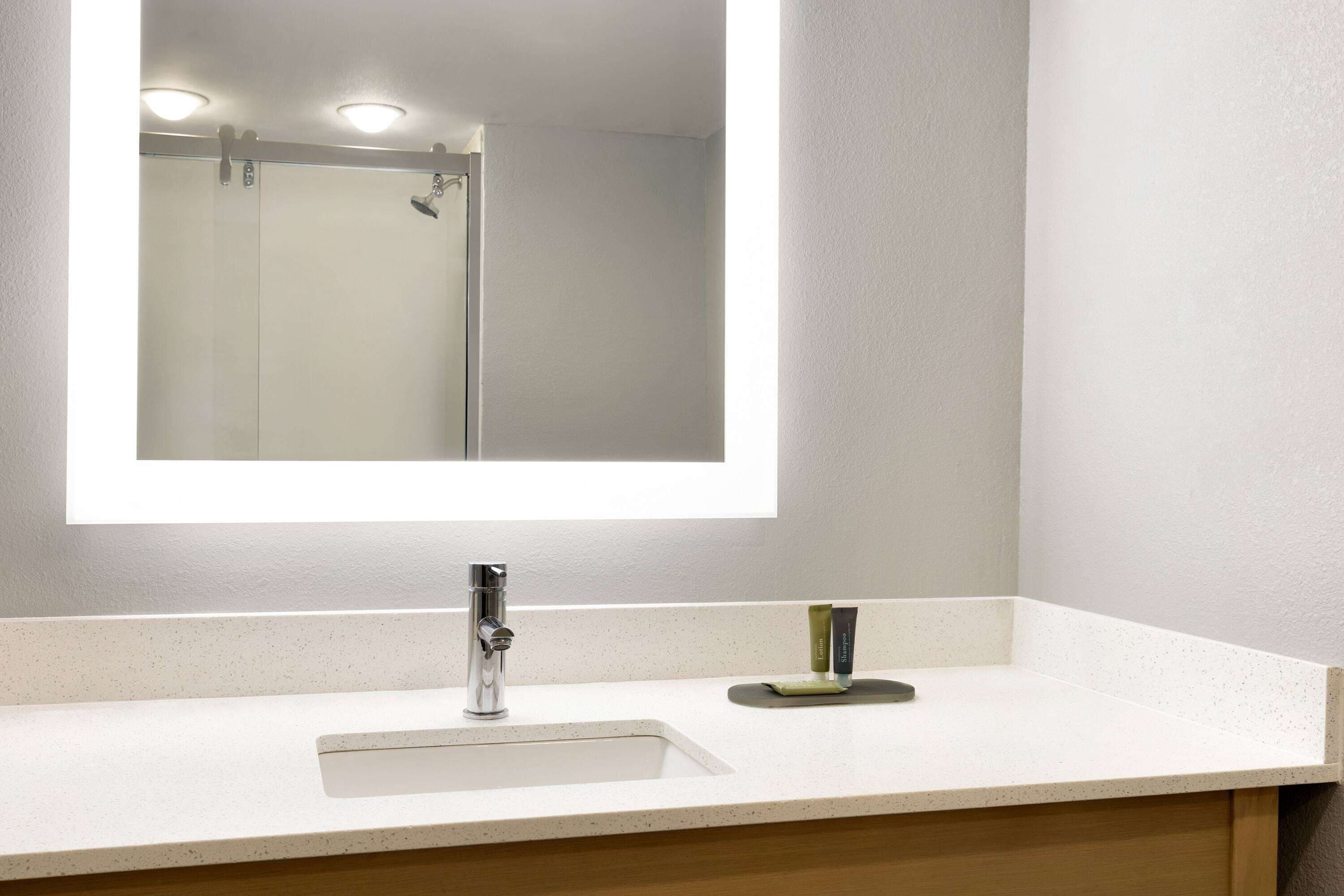 Un baño con lavamanos blanco, un lavabo, espejo y ducha.
