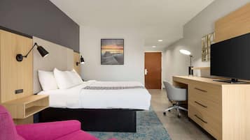 Een moderne hotelkamer met een bed, een bureau met een computer, een stoel en een televisie.