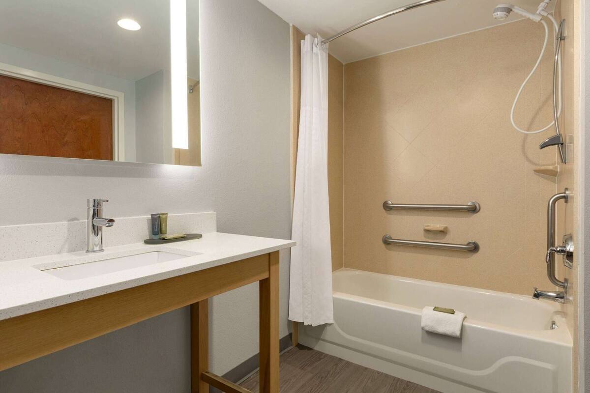 Une salle de bain avec un lavabo blanc, un miroir et une baignoire.