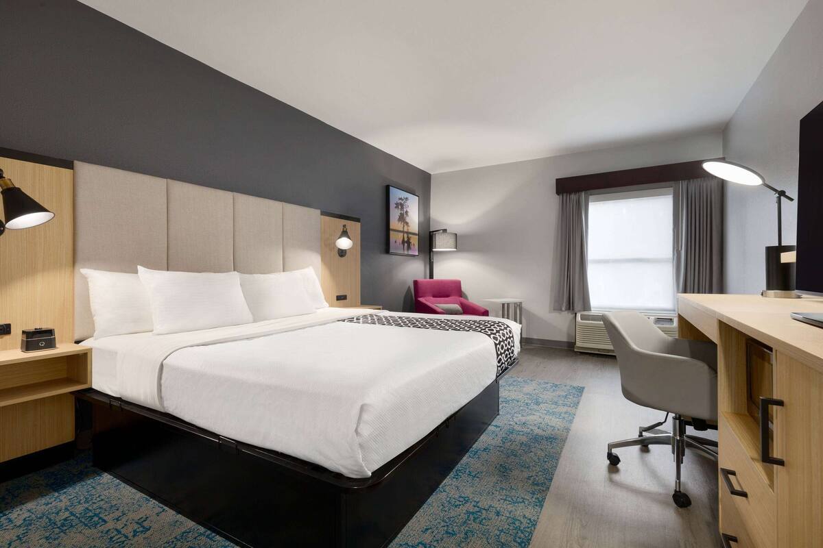 Une chambre d’hôtel avec un grand lit, un bureau, une chaise et une petite table.