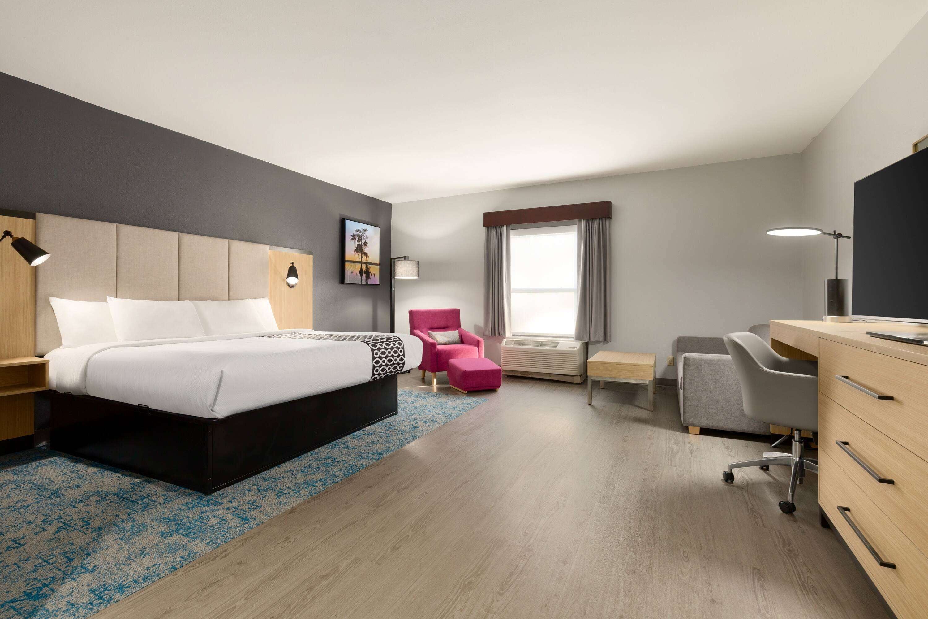Habitación de hotel con cama, escritorio, silla y un amplio ventanal.