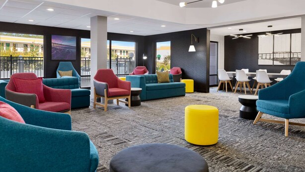 Un espace lounge moderne avec des sièges aux couleurs vives, de grandes fenêtres et une vue sur la ville.