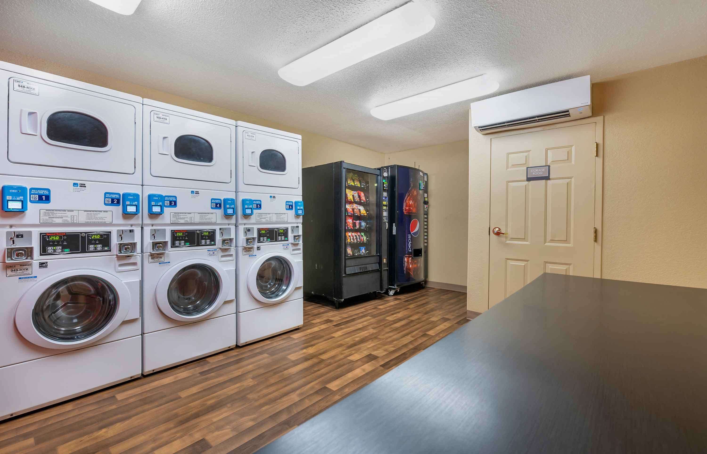A laundry room with multiple washing machines and two vending machines.