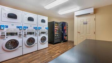 A laundry room with multiple washing machines and two vending machines.