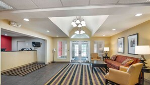 A hotel lobby with a reception desk, a sofa, a coffee table, a chandelier, and a striped rug. - Extended Stay America Suites Indianapolis West 86th St (Indianapolis)