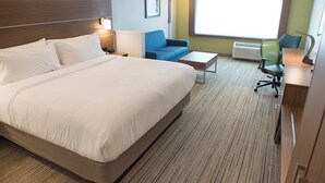 Habitación de hotel con una cama grande, un escritorio, una silla, un sofá y una ventana con vistas.