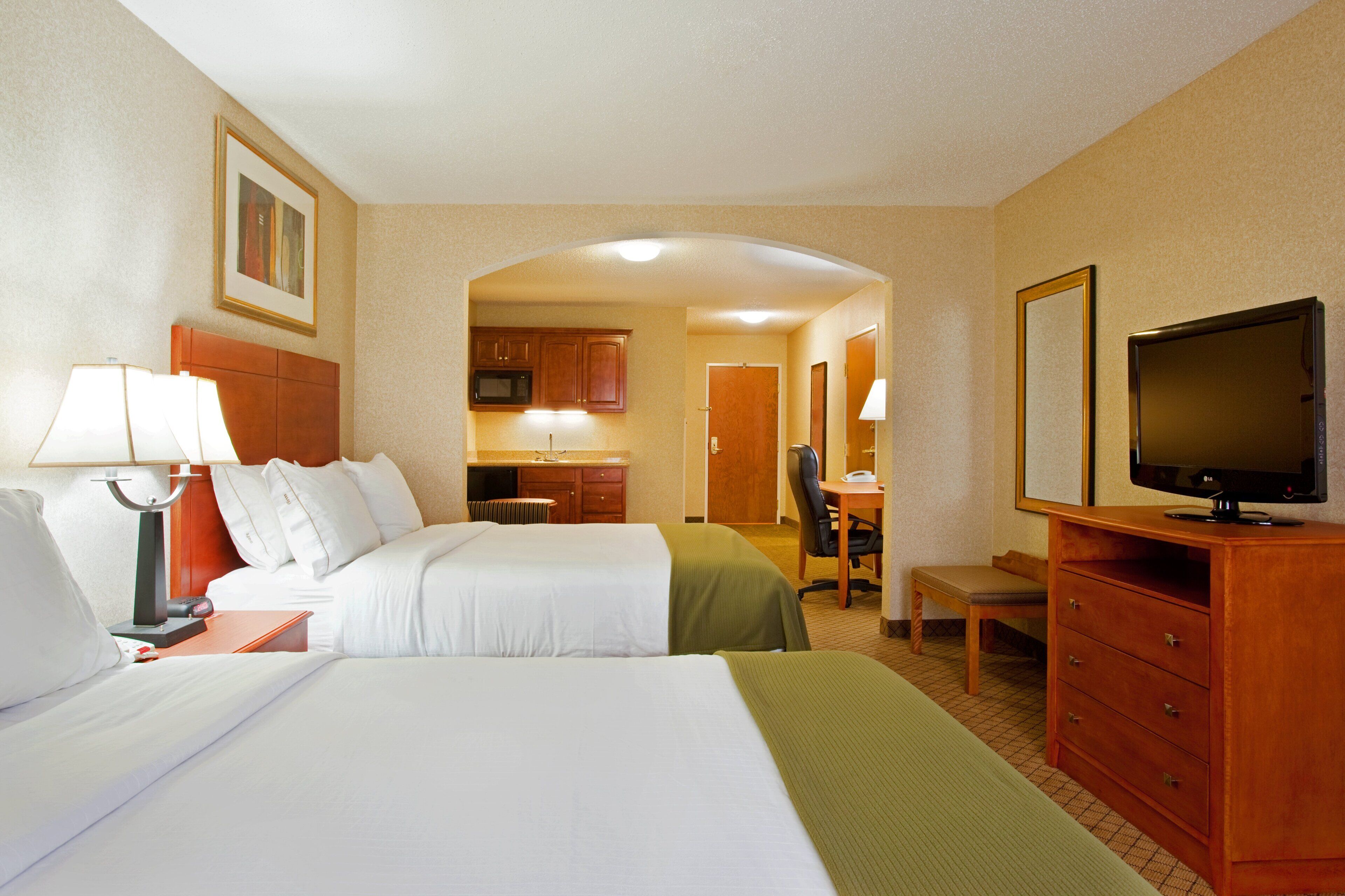 Une chambre d’hôtel avec deux lits, un bureau, une télévision et une kitchenette.