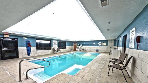 An indoor swimming pool with a skylight, tiled walls, and a poolside area with chairs. - Holiday Inn Express Hotel & Suites Goshen by IHG (Goshen)