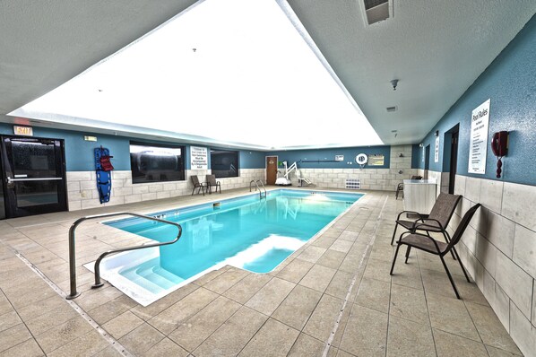 An indoor swimming pool with a skylight, tiled walls, and a poolside area with chairs. - Holiday Inn Express Hotel & Suites Goshen by IHG (Goshen)