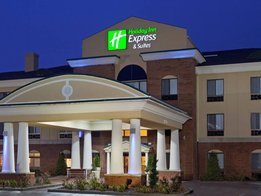 Et Holiday Inn Express & Suites hotel med overdækket indgang og murstensfacade.