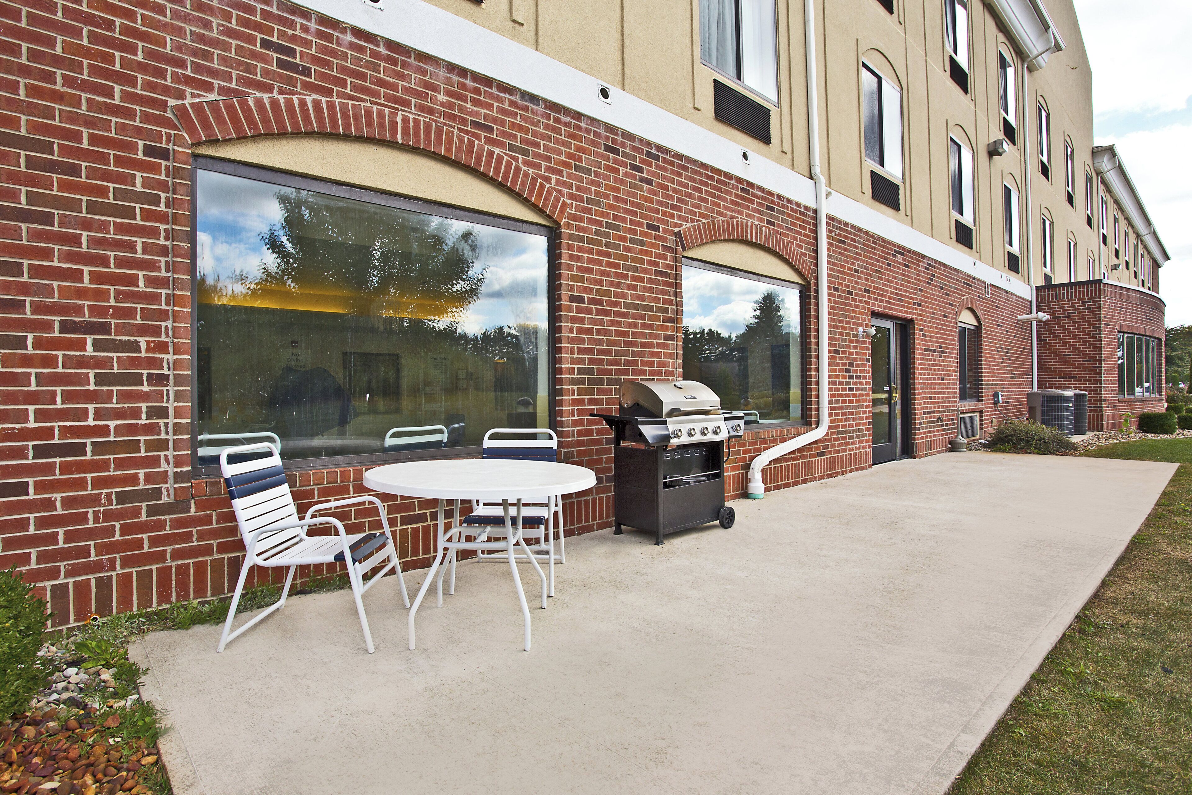 A brick building with a patio area featuring a grill and outdoor seating.
