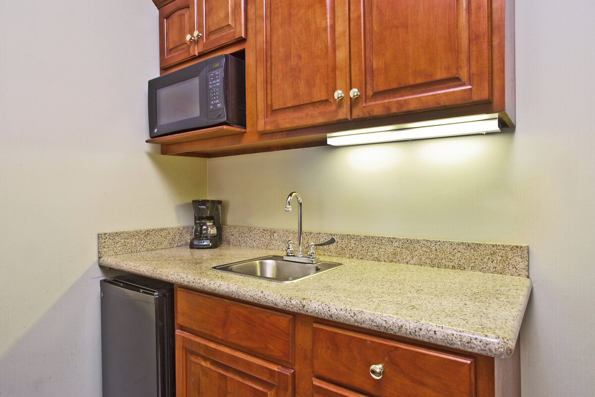 A kitchen with wooden cabinets, a stainless steel sink, a microwave, and a dishwasher.