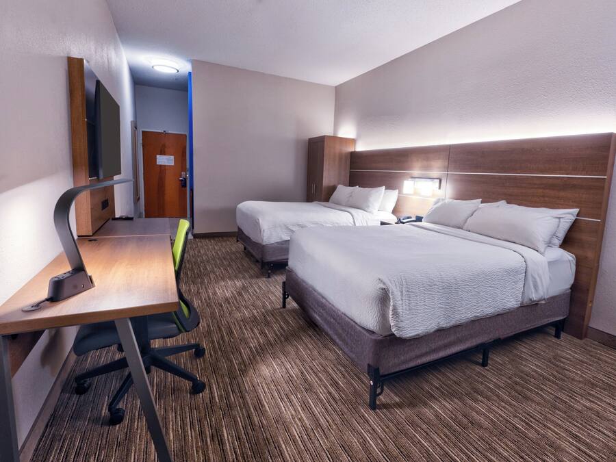 Habitación de hotel con dos camas, un escritorio y una silla.