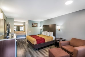 A hotel room with a bed, bedside table, lamp, and a television. - Econo Lodge Hesperia - Victorville I-15 (Hesperia)