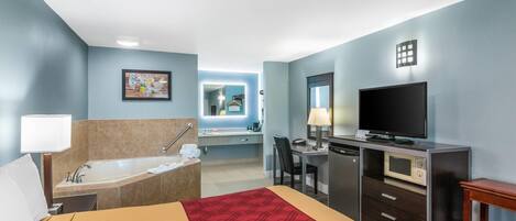 Une chambre d’hôtel équipée d’un lit, d’un bureau, d’une télévision, d’un four à micro-ondes et d’une salle de bain avec baignoire et lavabo.