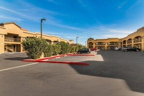 A parking lot with multiple cars, a clear blue sky, and buildings with balconies. - Econo Lodge Hesperia - Victorville I-15 (Hesperia)