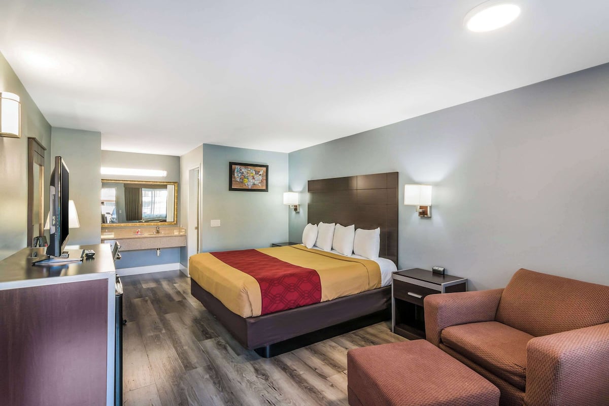 Ein Hotelzimmer mit Bett, Schreibtisch, Sessel und Fernseher.