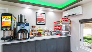 Un espace où l’on peut se servir soi-même pour le petit-déjeuner, comprenant une machine à café, un distributeur de jus et un grille-pain.