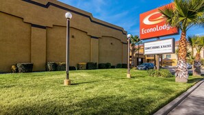 Un hotel con un cartel grande de EconoLodge, un césped bien cuidado y algunas palmeras.