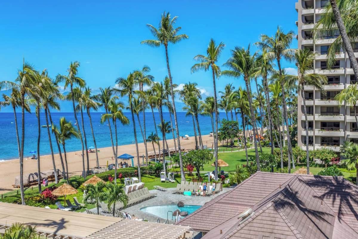 A resort with a pool, beach, and palm trees.