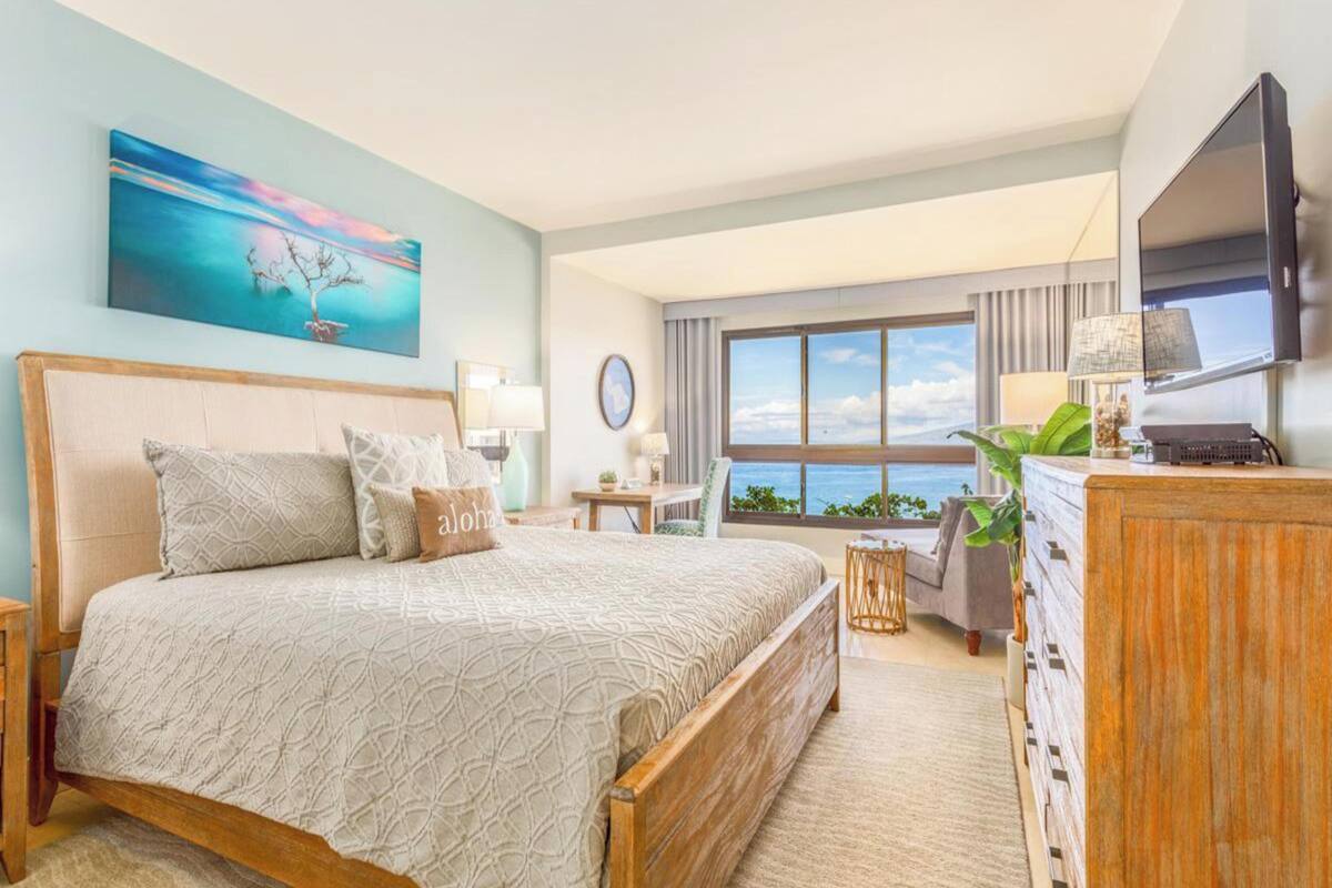 A hotel room with a bed, a desk, a TV, and a large window with a view.