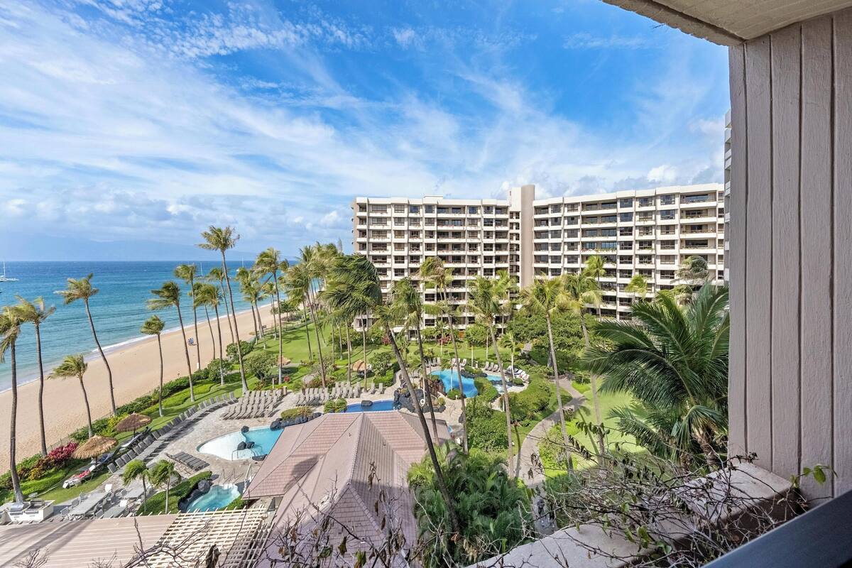 A resort with a pool area, palm trees, and a beach view.