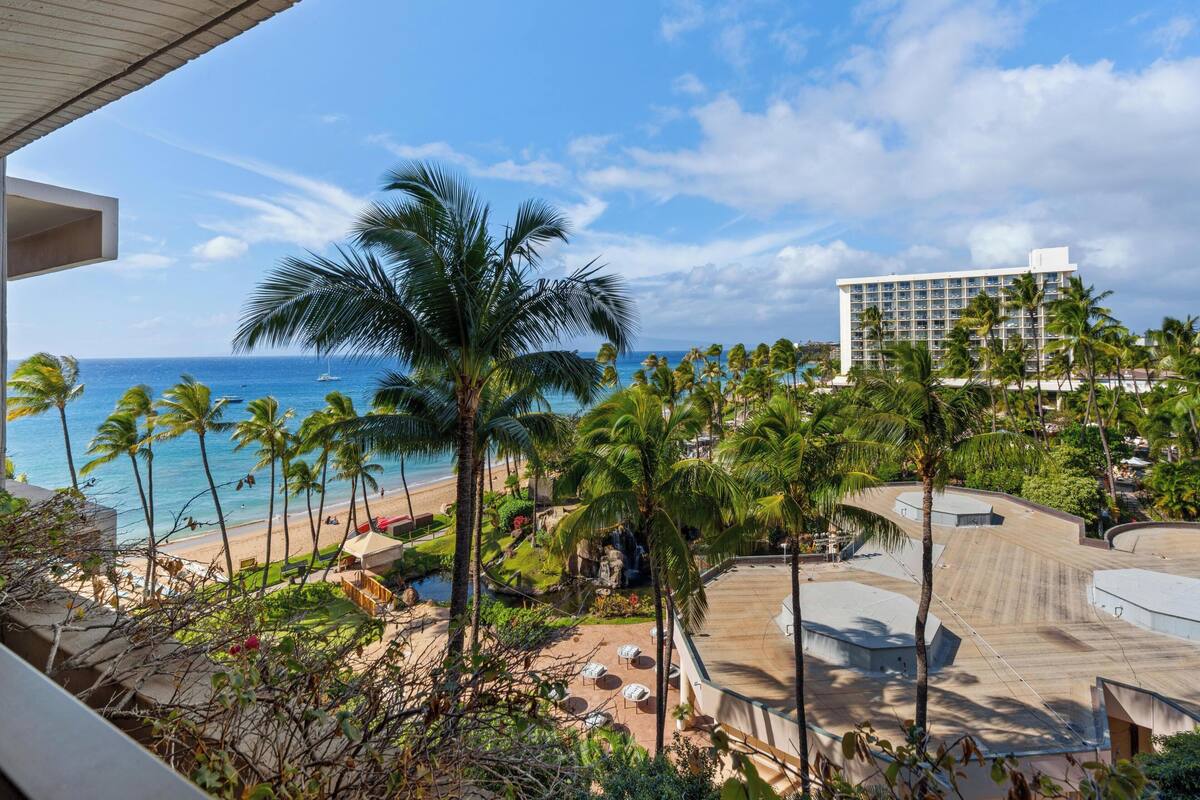 A resort with a pool, palm trees, and a beach view.