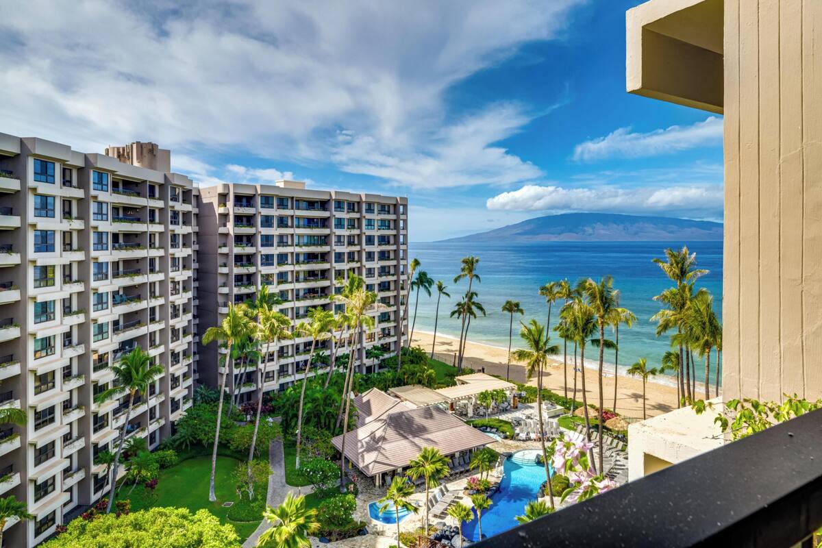 A hotel with multiple floors, a pool area, and a view of the beach and ocean.