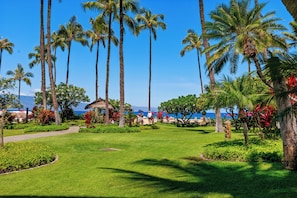 A tropical resort with palm trees, a pathway, and a view of the ocean. - Kaanapali Alii-2 Bedroom Ocean Views (Lahaina)