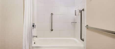 Un baño con una bañera blanca, barras de apoyo y una cortina de ducha.