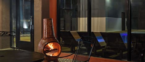 An outdoor seating area with a fire feature, lounge chairs, and a table.