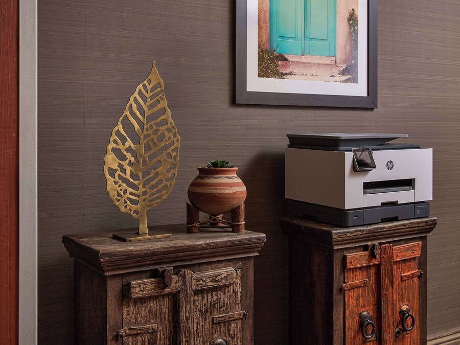 A wooden cabinet with a printer on top, a decorative leaf, and a small potted plant.