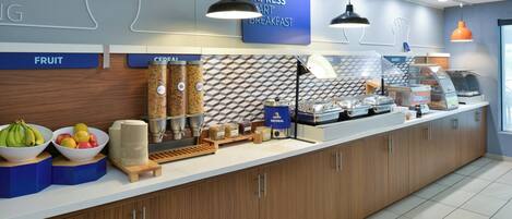 A breakfast area with a fruit bowl, cereal, and a bakery display.