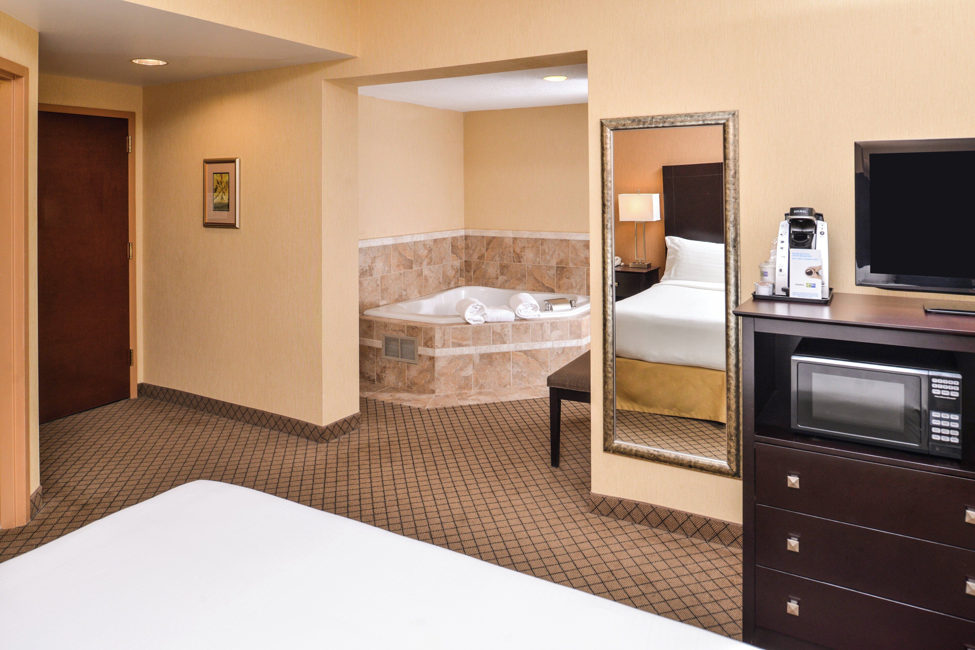 Une chambre d’hôtel comprenant un lit, une salle de bain avec baignoire, une machine à café et un téléviseur.