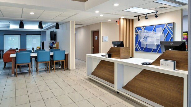 A hotel reception area with a modern design, featuring a reception desk, seating area with tables and chairs, and a large blue and white geometric wall decoration. - Holiday Inn Express Lewisburg/New Columbia by IHG (New Columbia)