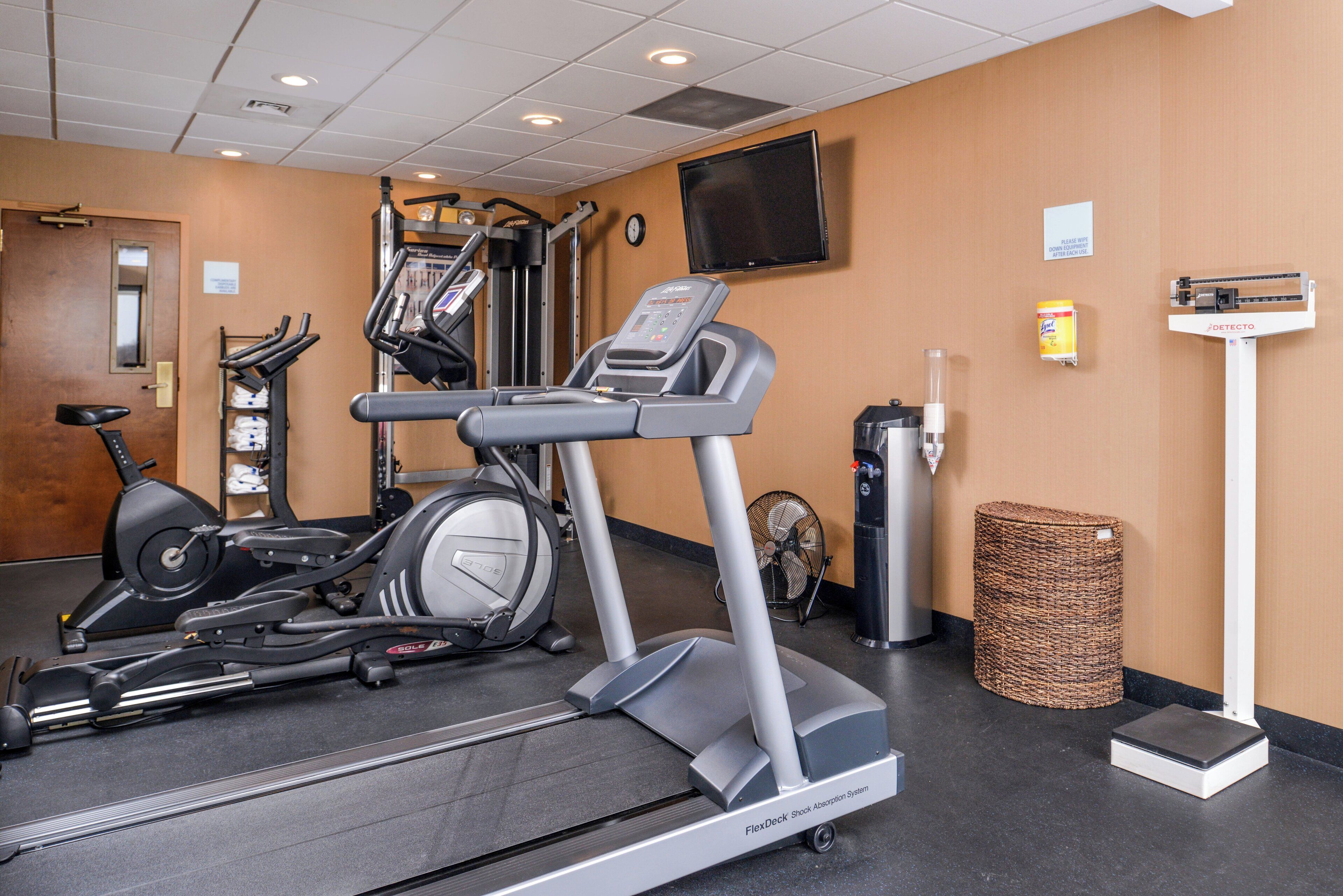 A gym with various exercise equipment including treadmills, stationary bikes, and a weight machine.