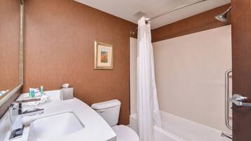 A bathroom with a white sink, toilet, and bathtub. There is a framed picture on the wall and a towel rack.