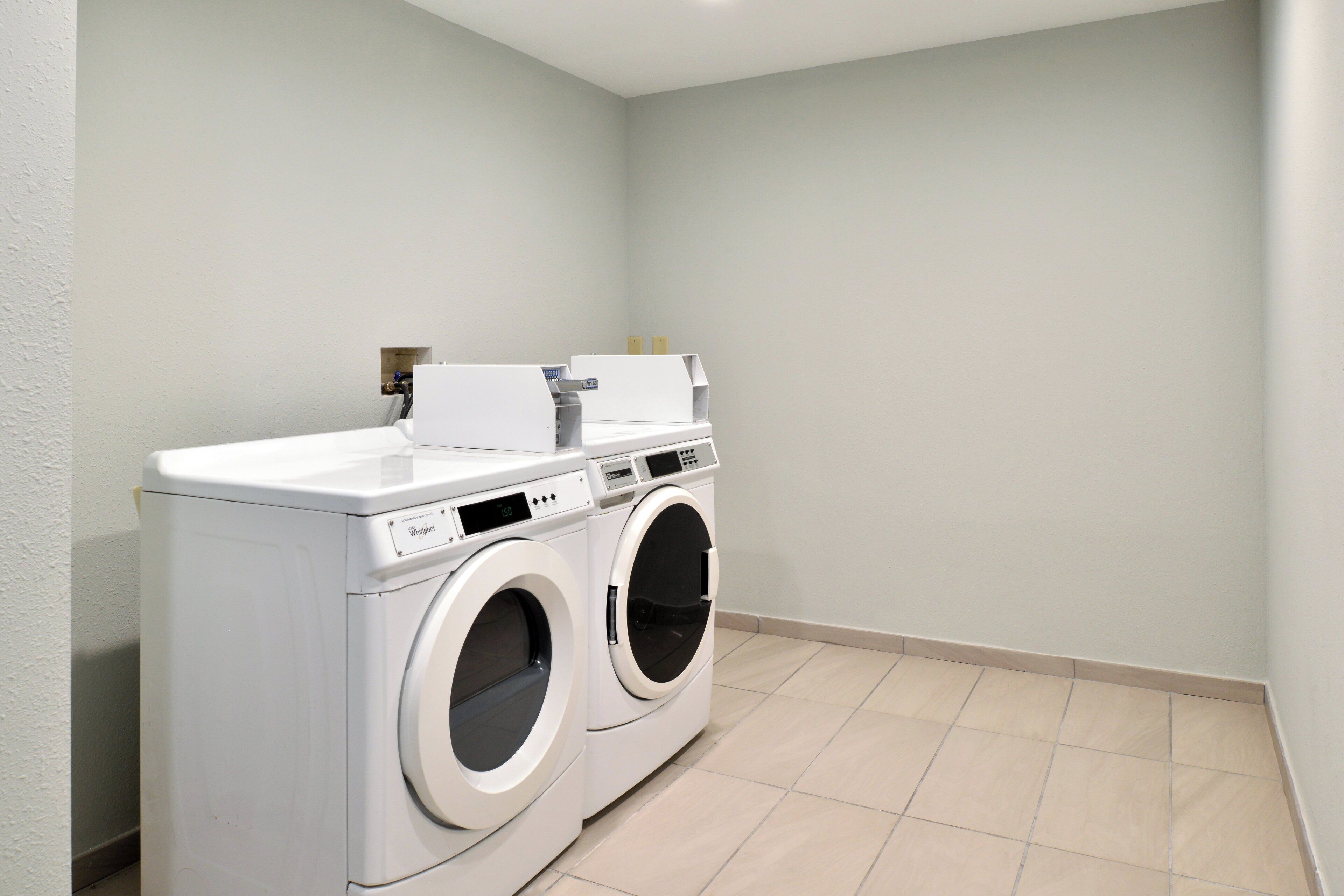 A laundry room with two front-loading washing machines and a dryer.