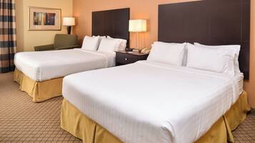 A hotel room with two beds, a nightstand, a lamp, a telephone, and a framed picture on the wall.