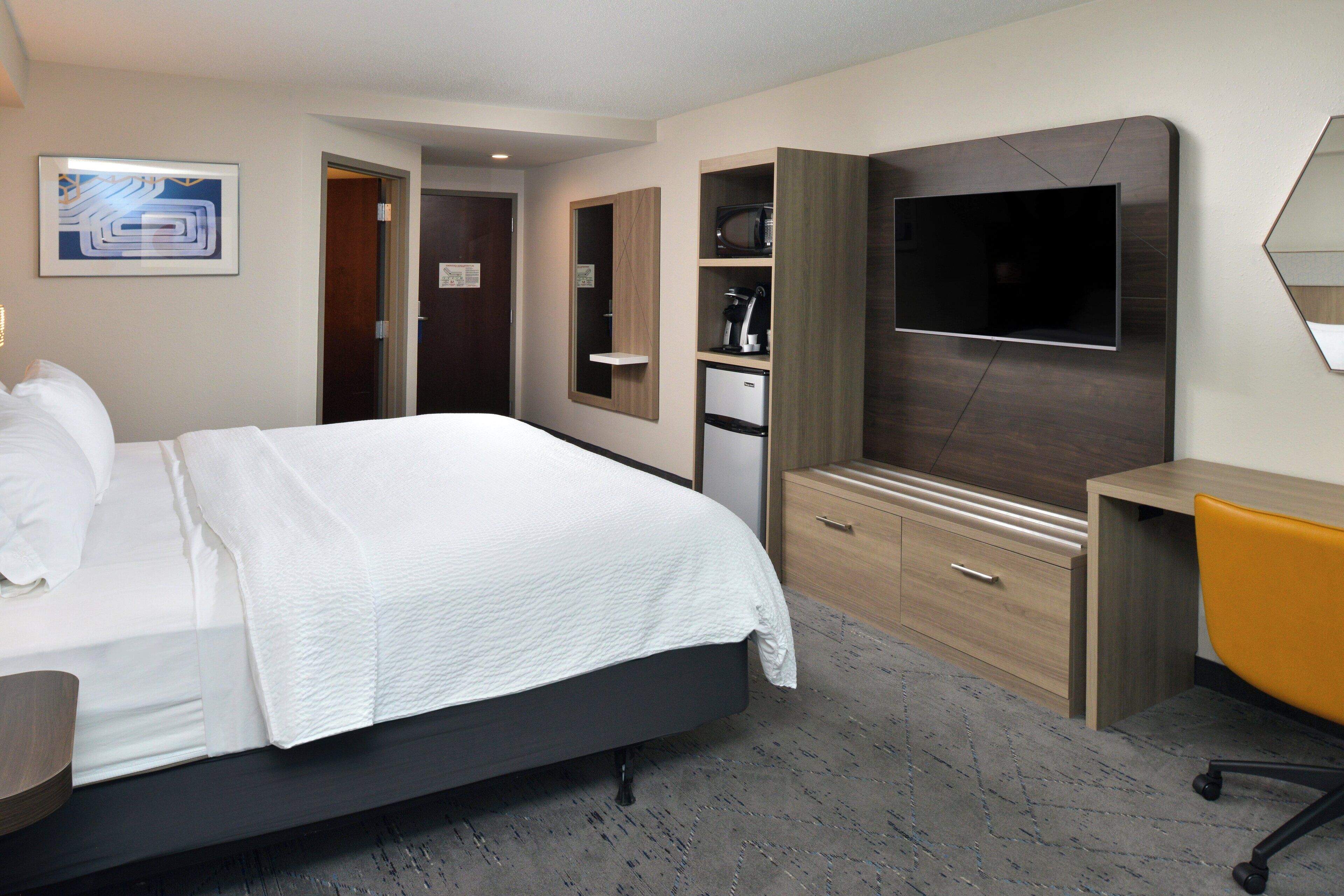 Een hotelkamer met een bed, een televisie, een bureau en een kledingkast.