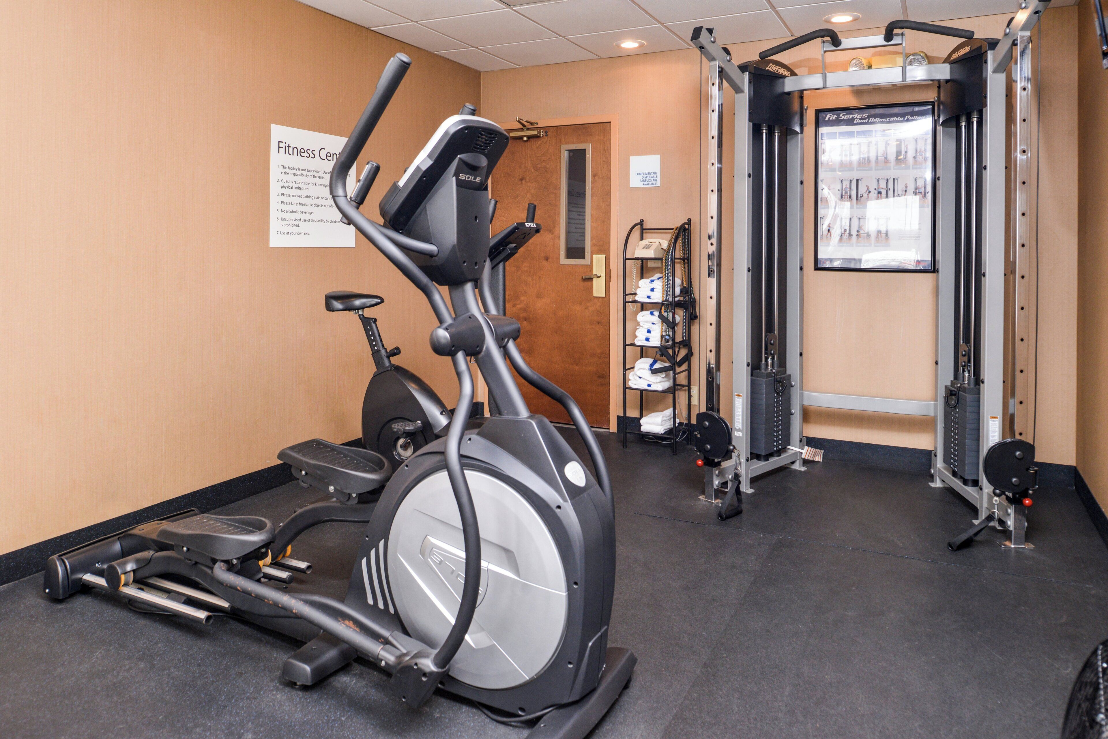 A fitness center with cardio equipment, weight machines, and a rack of towels.