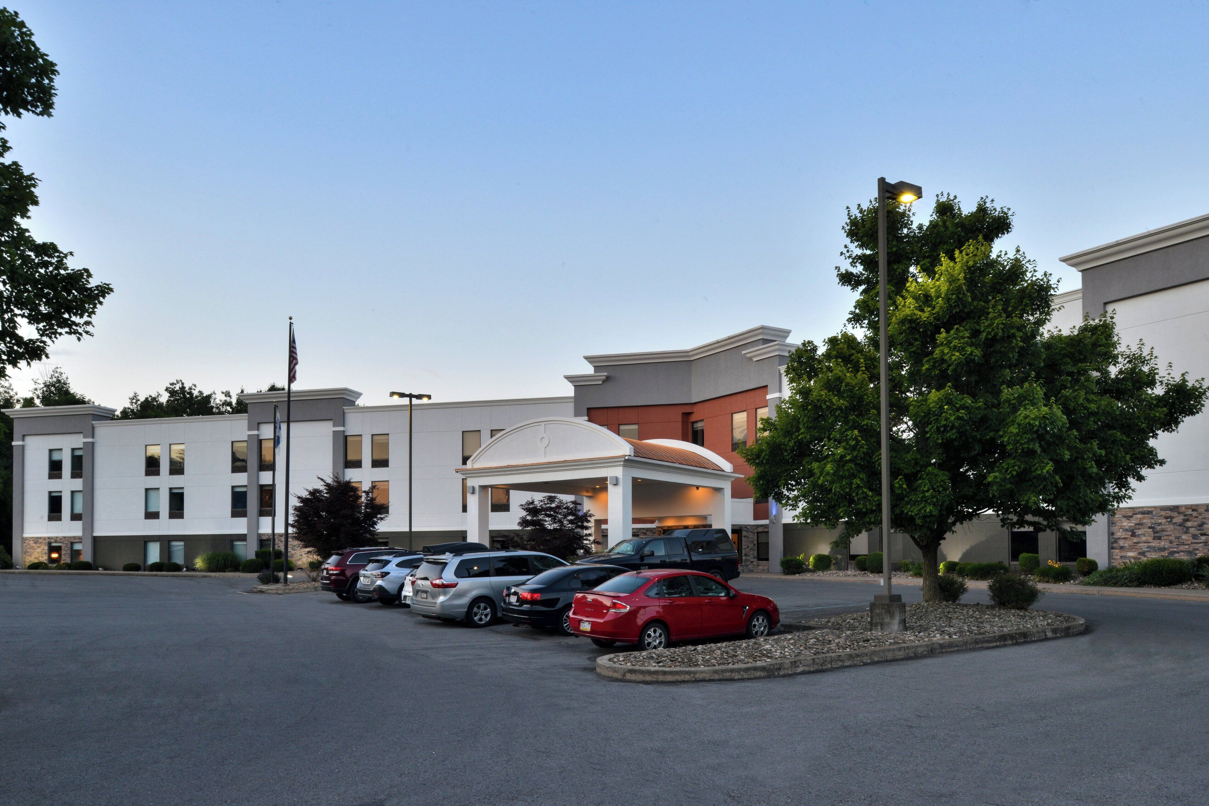 A hotel with a parking lot, multiple cars, and a well-maintained landscape.