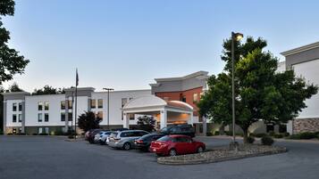 A hotel with a parking lot, multiple cars, and a well-maintained landscape.