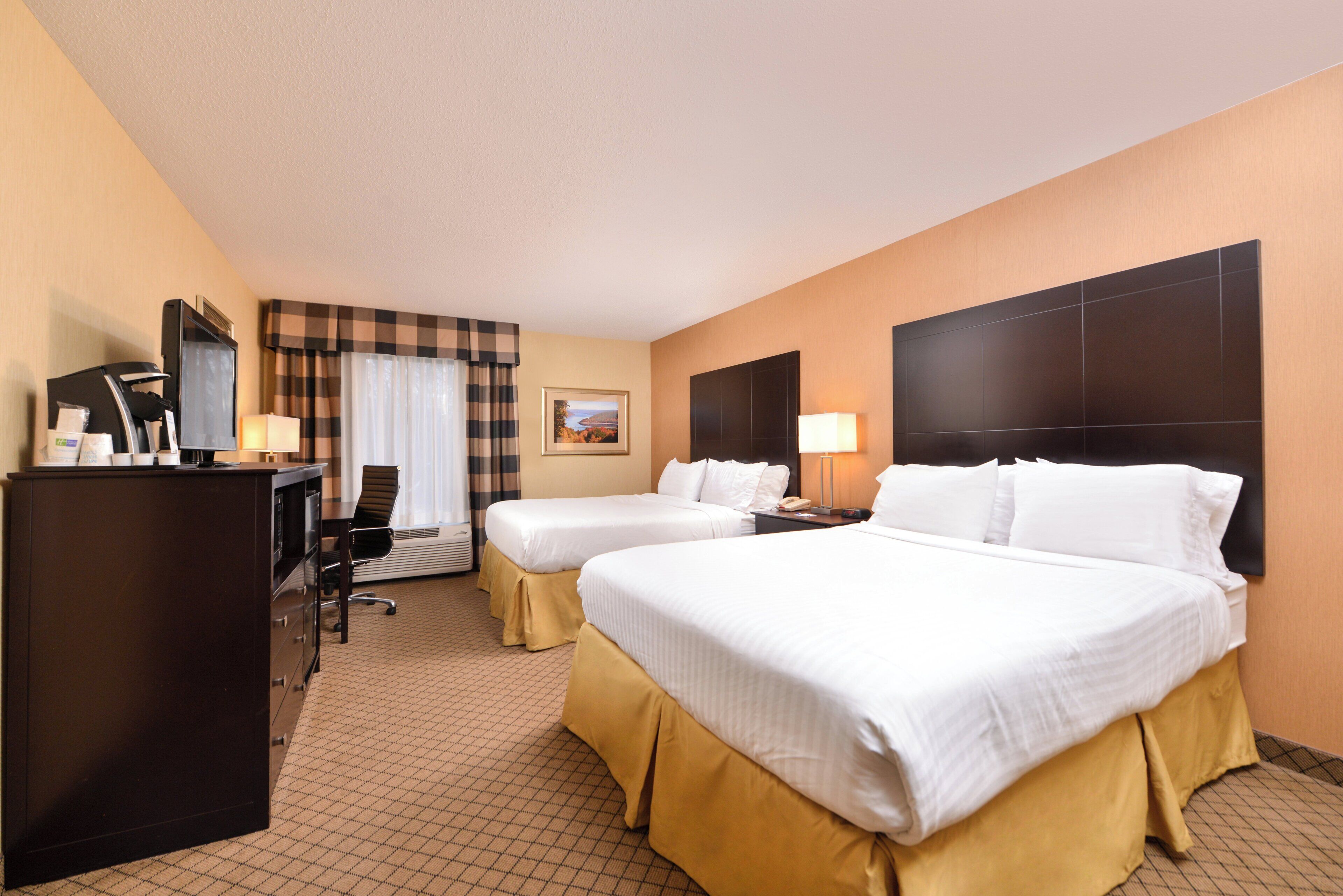 A hotel room with two beds, a desk, a chair, a desk lamp, a telephone, and a picture on the wall.