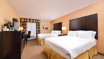 A hotel room with two beds, a desk, a chair, a desk lamp, a telephone, and a picture on the wall.