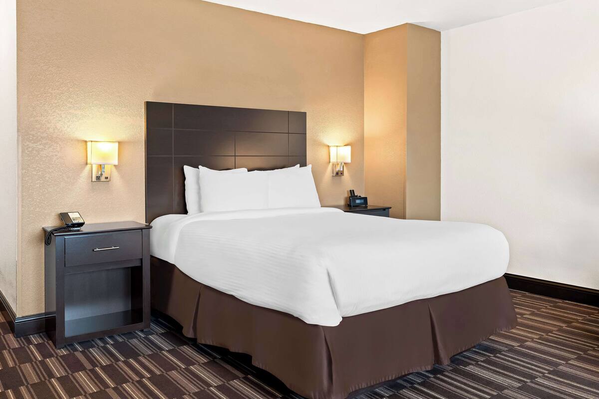 A hotel room with a large bed, two bedside tables with lamps, and a telephone on one table.