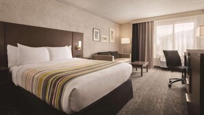 A hotel room with a large bed, a desk, a chair, and a sofa. - Country Inn & Suites by Radisson, Mt. Pleasant-Racine West, WI (Mount Pleasant)