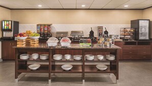 A buffet setup with various food items and a refrigerator. - Country Inn & Suites by Radisson, Mt. Pleasant-Racine West, WI (Mount Pleasant)
