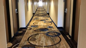 A long, narrow hotel corridor with a patterned carpet, doors on both sides, and a ceiling light. - Country Inn & Suites by Radisson, Mt. Pleasant-Racine West, WI (Mount Pleasant)